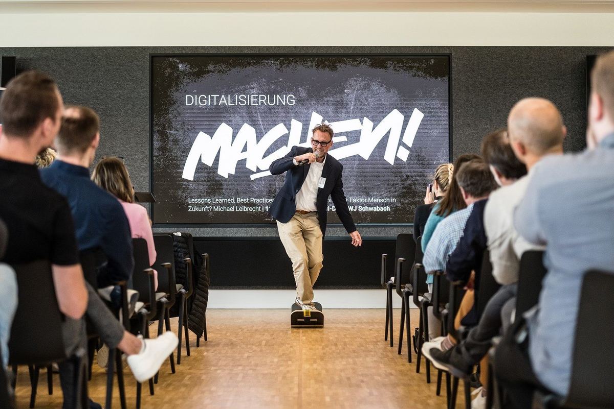 Michael Leibrecht hält eine Keynote, auf der Leinwand steht MACHEN